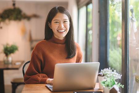happy woman in front of laptop looking for savings account